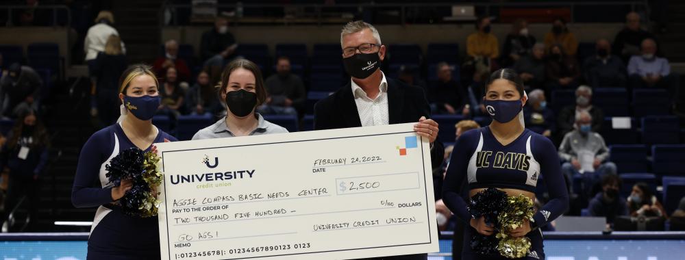 University Credit Union presents check to Aggie Compass at basketball game